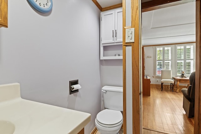 bathroom featuring toilet, wood-type flooring, and baseboards