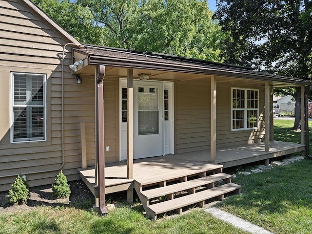 view of exterior entry with covered porch and a lawn