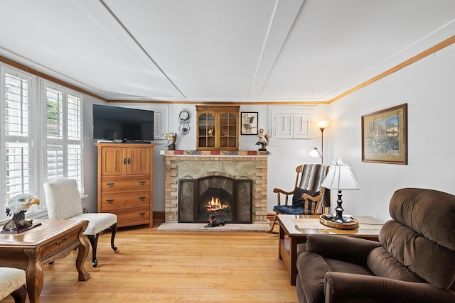 living area with light wood-type flooring, a fireplace, and crown molding