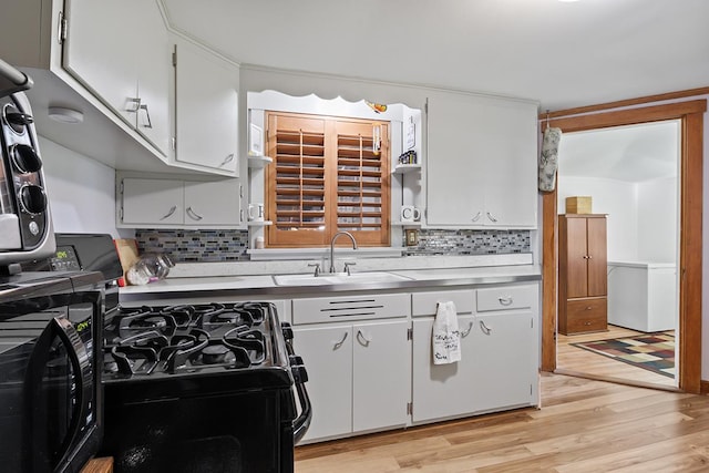 kitchen featuring gas range oven, a sink, light wood-style flooring, and white cabinets