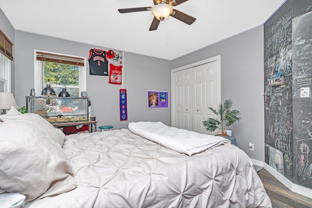 bedroom featuring ceiling fan, a closet, baseboards, and wood finished floors