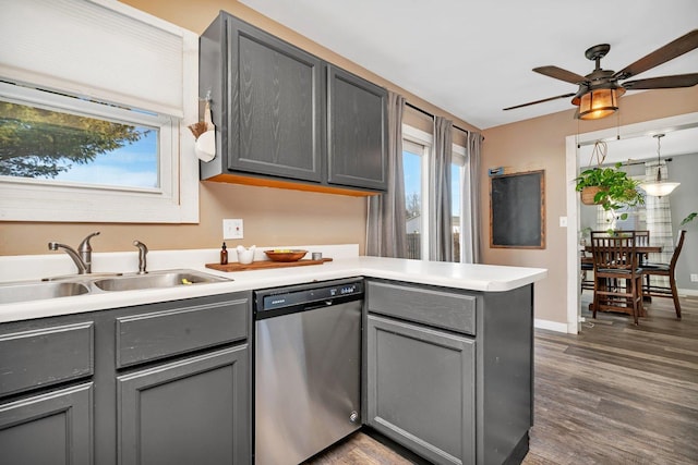 kitchen with a sink, a peninsula, gray cabinets, and dishwasher