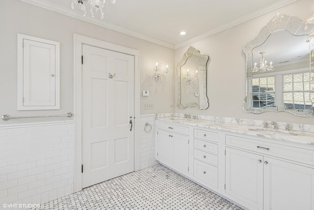 full bathroom featuring a wainscoted wall, tile walls, a sink, and ornamental molding