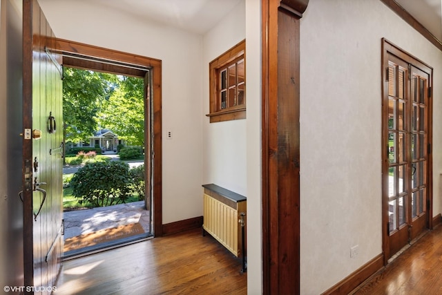 doorway to outside with radiator, baseboards, and wood finished floors