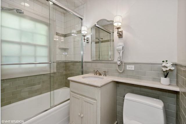 bathroom with toilet, vanity, tile walls, and enclosed tub / shower combo