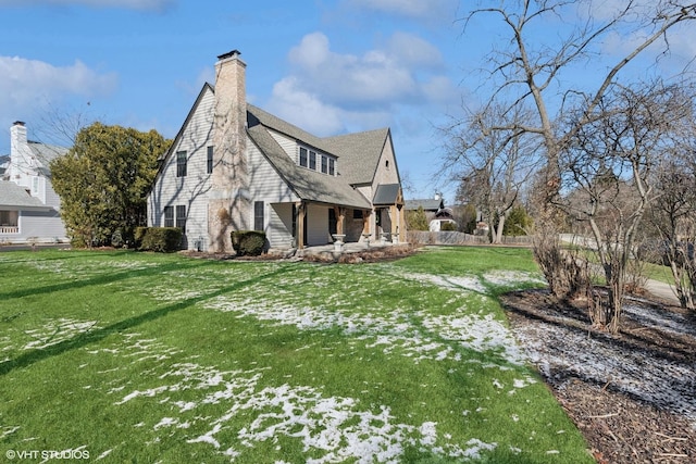 view of side of property with a porch, a lawn, and a chimney