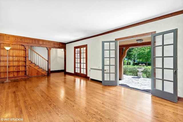 unfurnished living room featuring a healthy amount of sunlight, radiator heating unit, wood finished floors, and french doors