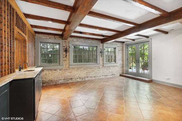 unfurnished sunroom featuring beam ceiling, a sink, and french doors