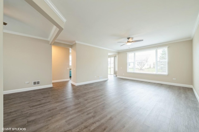 spare room featuring crown molding, dark wood finished floors, visible vents, ceiling fan, and baseboards