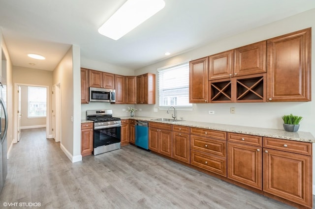 kitchen with stainless steel appliances, a sink, a wealth of natural light, and brown cabinets