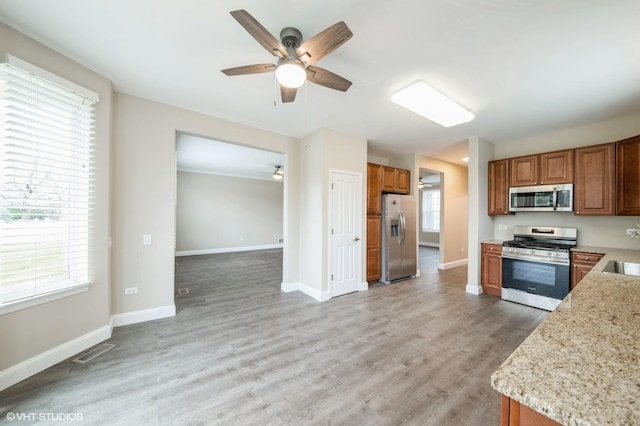 kitchen featuring stainless steel appliances, visible vents, brown cabinetry, light wood-style floors, and baseboards