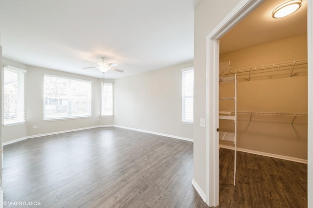 interior space with a ceiling fan, baseboards, and wood finished floors