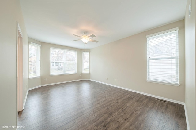 spare room featuring visible vents, dark wood finished floors, baseboards, and ceiling fan