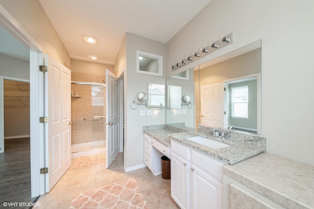 bathroom with vanity, baseboards, a spacious closet, tile patterned floors, and a stall shower