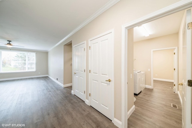 hall with ornamental molding, visible vents, independent washer and dryer, and wood finished floors