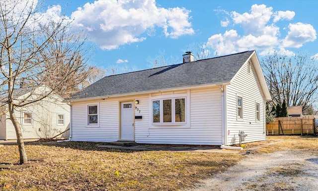 view of front of property with roof with shingles, fence, and a chimney