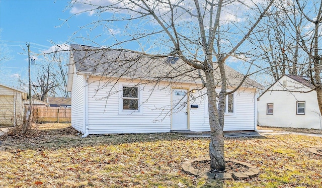 view of front facade with a shingled roof and fence