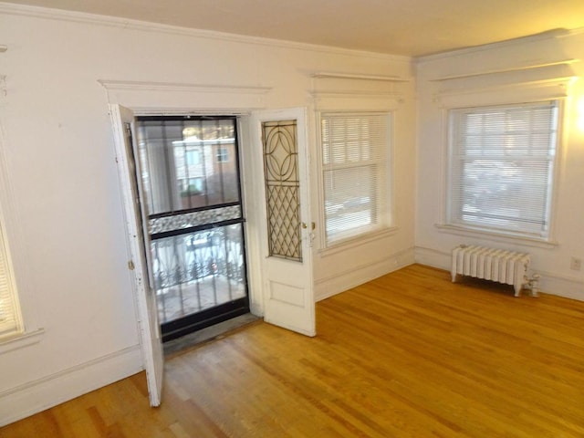 doorway to outside with baseboards, ornamental molding, light wood-style flooring, and radiator