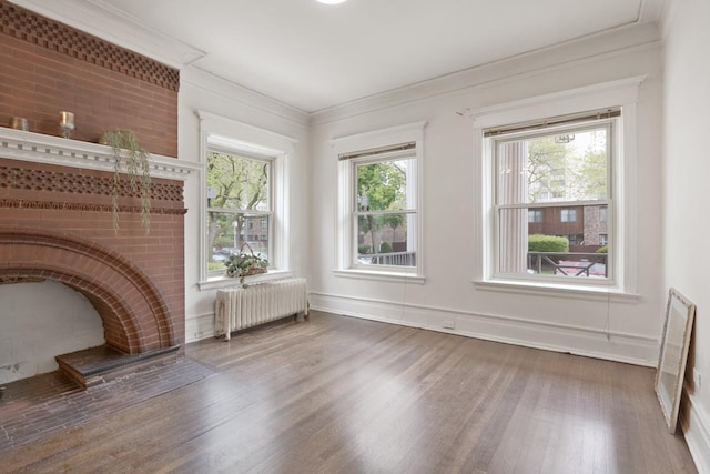 unfurnished living room featuring crown molding, wood finished floors, a wealth of natural light, and radiator