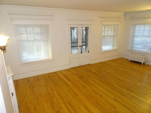 foyer with radiator heating unit, wood finished floors, and a healthy amount of sunlight