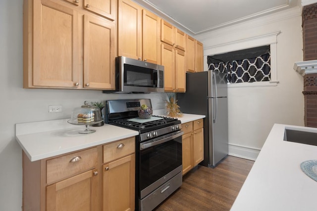 kitchen with light brown cabinets, dark wood-style flooring, light countertops, ornamental molding, and appliances with stainless steel finishes