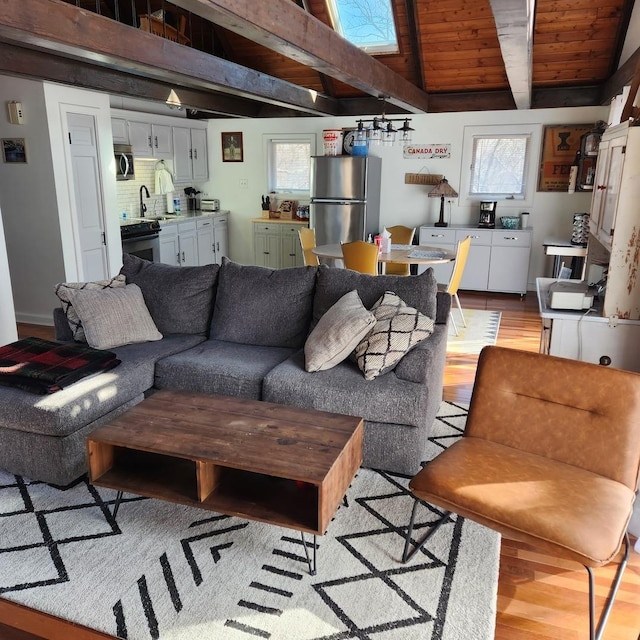 living area with lofted ceiling with beams and light wood-style floors