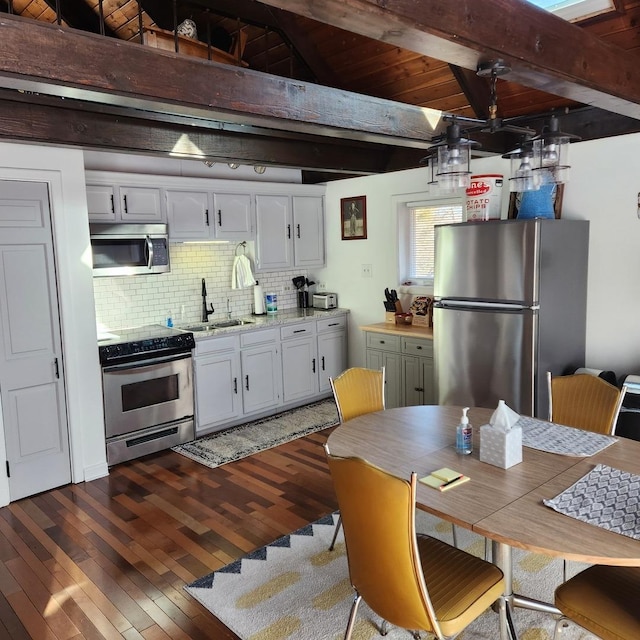 kitchen with stainless steel appliances, light countertops, backsplash, dark wood-type flooring, and beamed ceiling