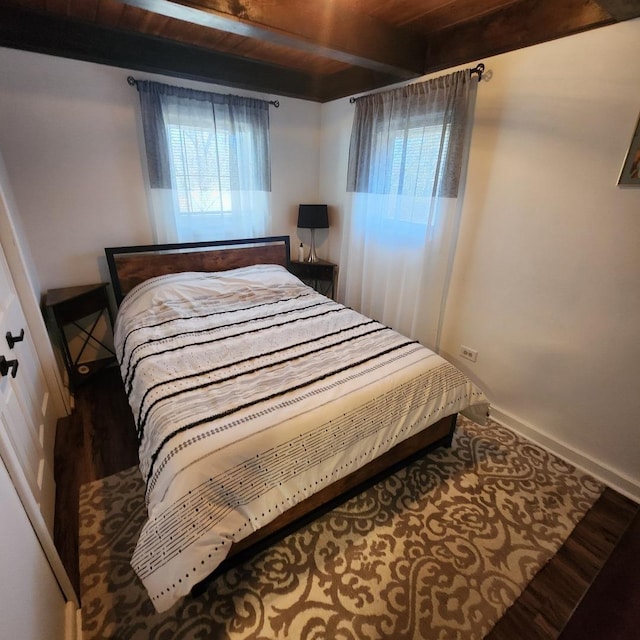 bedroom featuring wood ceiling, wood finished floors, beam ceiling, and baseboards