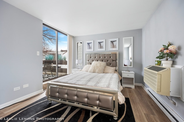 bedroom featuring a wall unit AC, dark wood-type flooring, baseboards, baseboard heating, and expansive windows