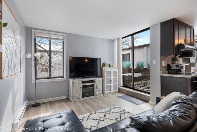 living area with baseboards, a glass covered fireplace, light wood-style flooring, expansive windows, and baseboard heating