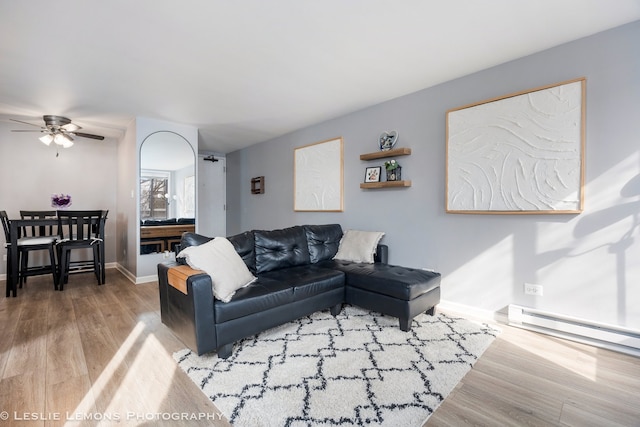 living area with a ceiling fan, baseboards, baseboard heating, and wood finished floors