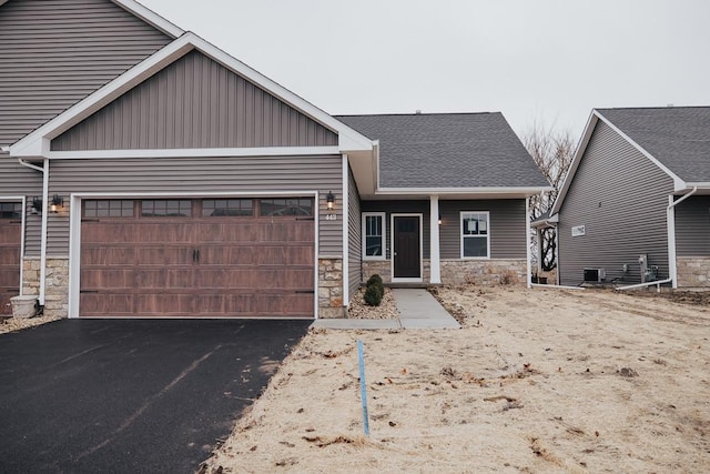 craftsman-style house with a garage, stone siding, aphalt driveway, and board and batten siding