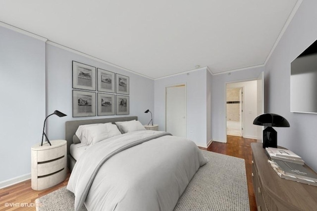 bedroom with ornamental molding, wood finished floors, and baseboards