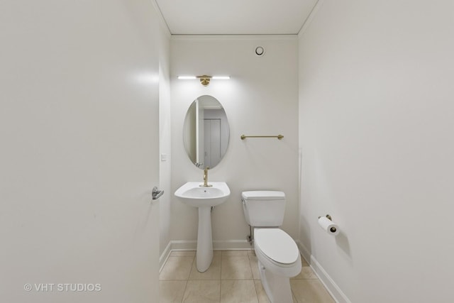 bathroom featuring toilet, tile patterned flooring, baseboards, and crown molding