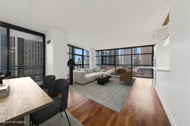 living room featuring a view of city, wood finished floors, visible vents, and floor to ceiling windows