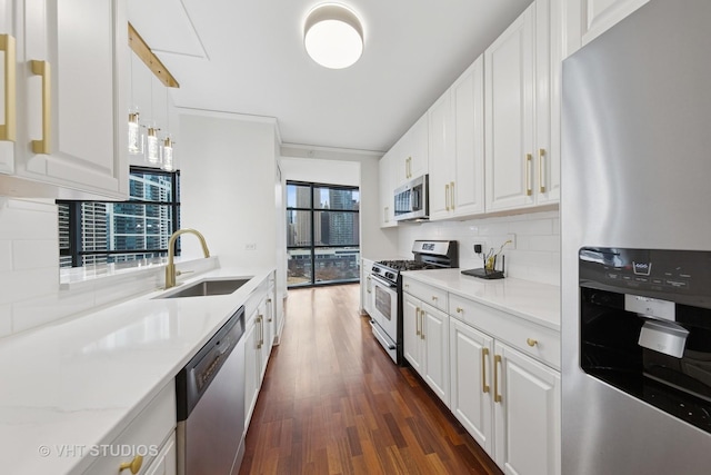 kitchen featuring tasteful backsplash, white cabinets, dark wood finished floors, stainless steel appliances, and a sink