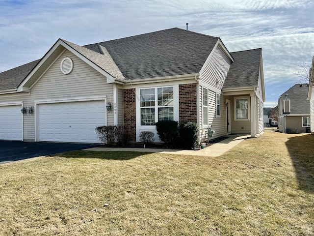 view of front of house featuring brick siding, a shingled roof, an attached garage, driveway, and a front lawn