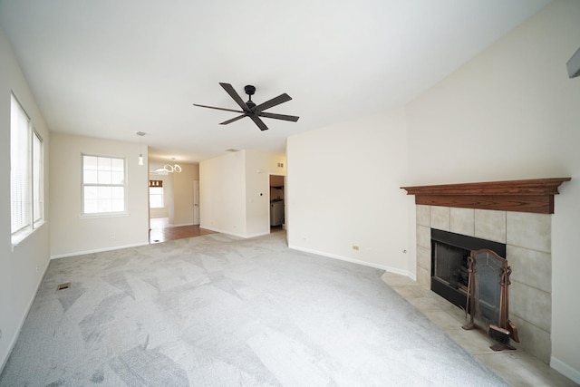 unfurnished living room featuring light carpet, a fireplace, baseboards, and ceiling fan