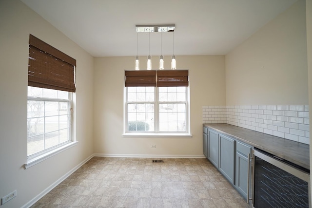 unfurnished dining area with wine cooler, visible vents, and baseboards