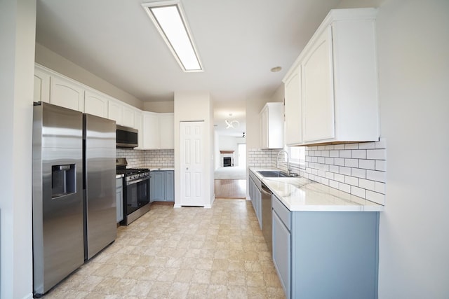 kitchen with stainless steel appliances, tasteful backsplash, a sink, and white cabinets