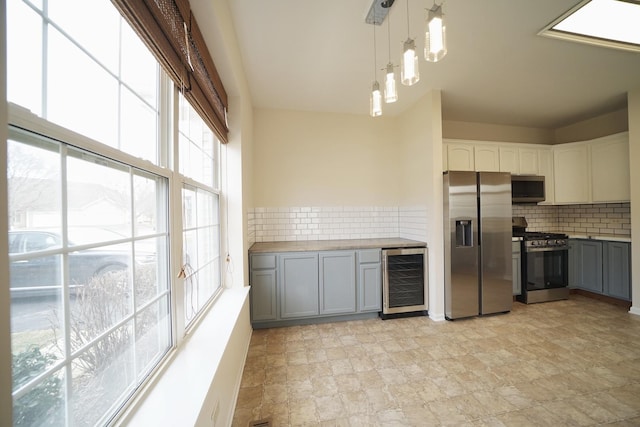 kitchen with beverage cooler, appliances with stainless steel finishes, backsplash, and gray cabinetry