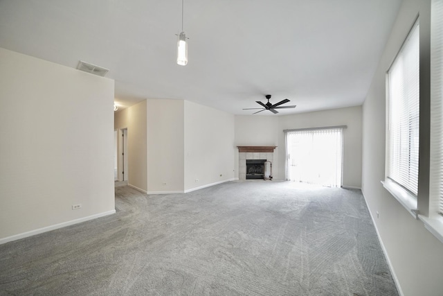 unfurnished living room featuring carpet floors, a fireplace, visible vents, ceiling fan, and baseboards