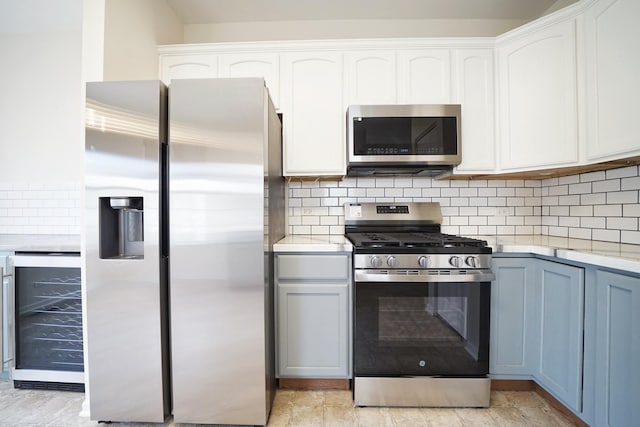 kitchen featuring light countertops, appliances with stainless steel finishes, wine cooler, and tasteful backsplash