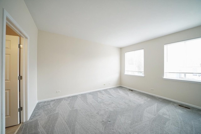 empty room featuring carpet floors, baseboards, and visible vents