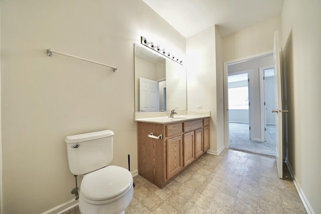 half bathroom with baseboards, vanity, and toilet