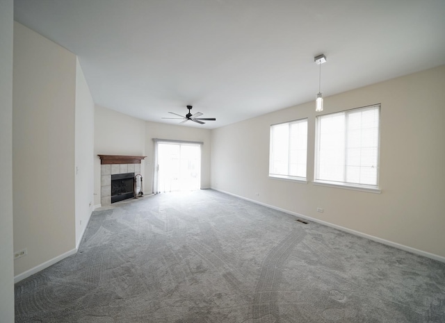 unfurnished living room with visible vents, baseboards, a tile fireplace, ceiling fan, and carpet floors