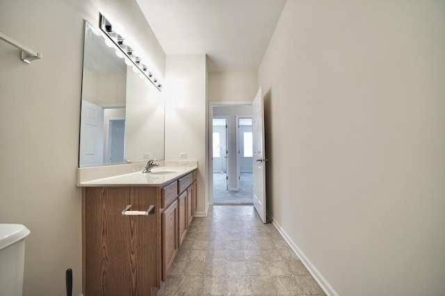 bathroom featuring toilet, vanity, and baseboards