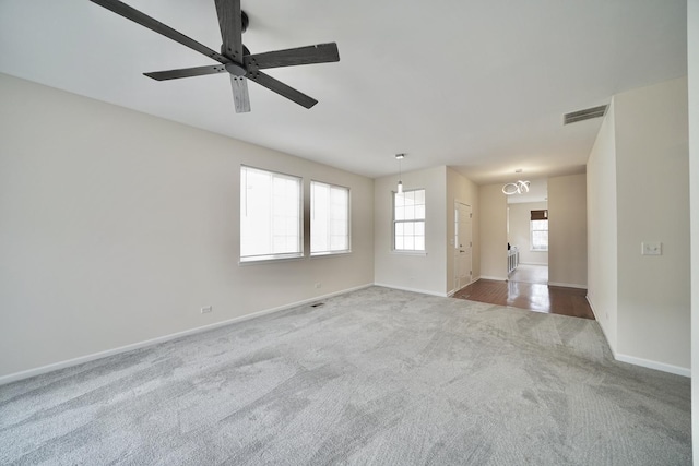 carpeted empty room featuring a ceiling fan, visible vents, and baseboards