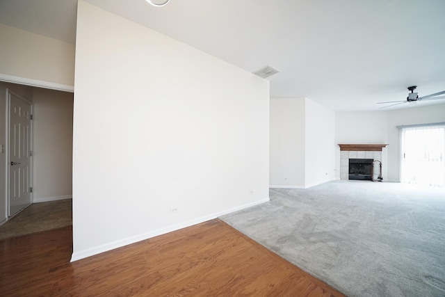 unfurnished living room featuring baseboards, visible vents, a tiled fireplace, ceiling fan, and carpet flooring