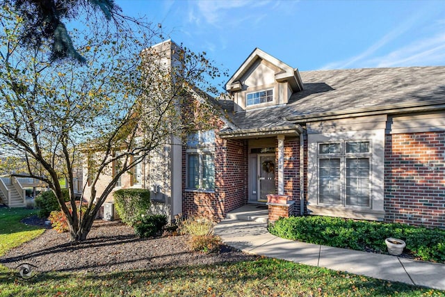 view of front of home featuring brick siding and roof with shingles